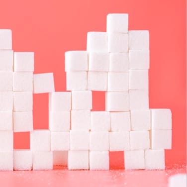 Sugar cubes stacked with a pink background